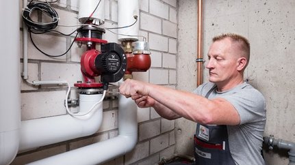 Fachmann installiert eine Wasserpumpe in einem Keller Ein Handwerker arbeitet konzentriert an einer Wasserpumpe in einem Keller, um die Installation zu überprüfen.
