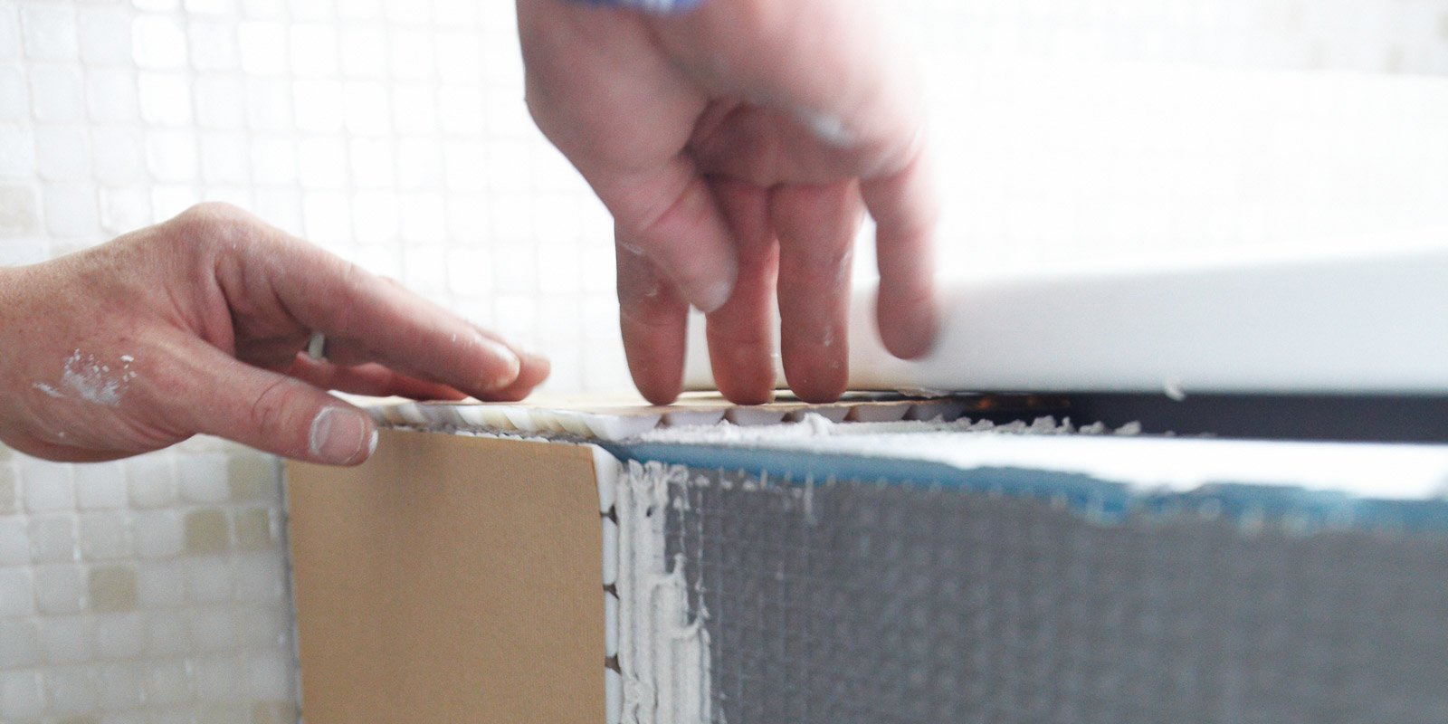 Eine Hand drückt sanft auf eine Kante, während die andere Hand die Position überprüft, um eine präzise Installation zu gewährleisten.