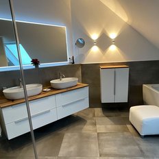 Ein modernes Badezimmer mit zwei Waschbecken auf einem Holzregal und einer eleganten Badewanne in einem hellen Raum.
