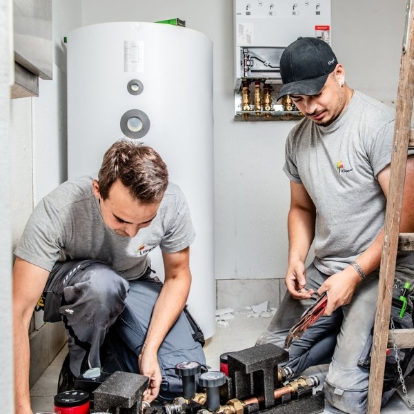 In einem hellen Raum überprüfen zwei Techniker sorgfältig die Rohrleitungen und Armaturen für eine Heizungsanlage.
