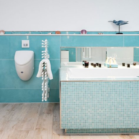 Ein modernes Badezimmer mit türkisfarbenen Fliesen, einer Badewanne und einem eleganten Waschbecken, das einladend wirkt.
