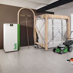 Ein moderner Heizkessel steht neben einem großen, stabilen Holzrahmen mit einer weißen Folie, der in einem Raum platziert ist.