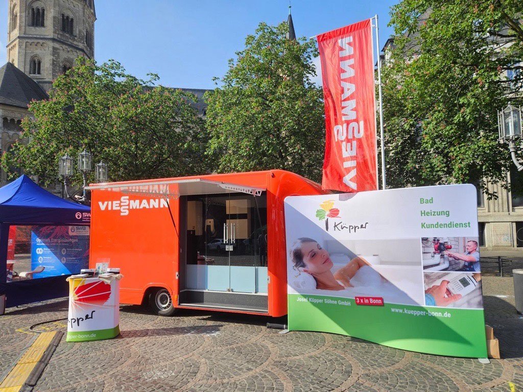 Der Verkaufsstand von Küpper bietet Dienstleistungen im Bereich Bad und Heizung an, mit einem großen Werbeschild im Vordergrund.