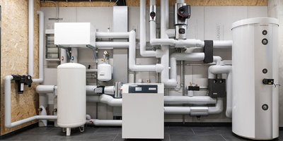 Eine moderne Heizungsanlage mit zahlreichen Rohren und einem großen weißen Wassertank an der Wand.